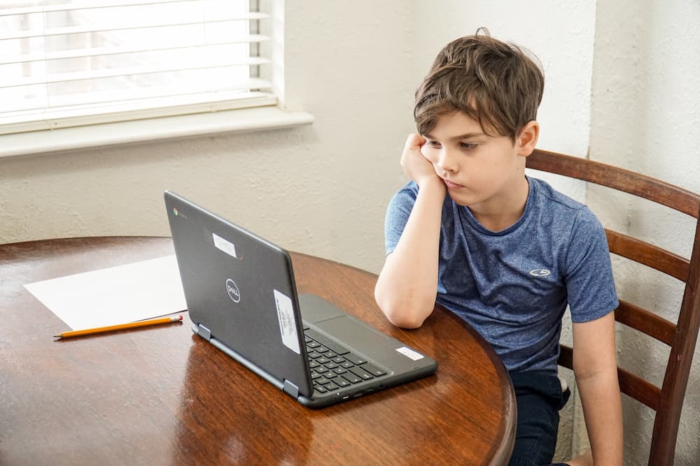 Μαθητής κάθεται βαριεστημένα μπροστά από τον υπολογιστή του.